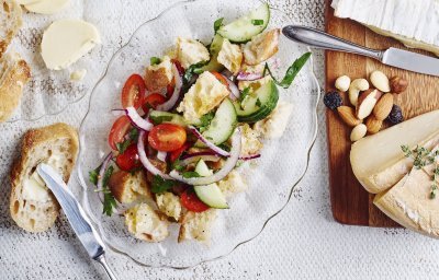 Een glazen schaaltje, ovaalvormig, gevuld met knapperige croutons, tomatenstukjes en komkommermaantjes.  