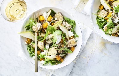 Een heerlijke aardappelsalade geserveerd in een diep wit bord. De kleuren zijn heerlijk fris en zonnig om je feestmenu te laten stralen. Groen, oranje en wit zijn hier de kleurtoppers. 