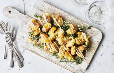 Eens een patatje in een feestjas op tafel? Serveer deze ovenaardappeltjes en ontvang veel "mmmmm-lekker complimentjes". Deze gecrushte aardappeltjes zijn geserveerd op een houten plank met een heerlijk picklessausje.  