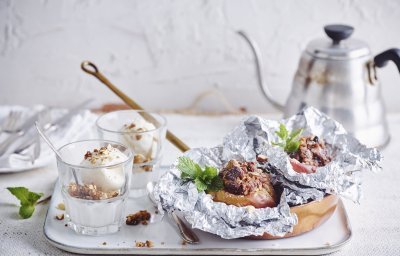 Een vers gepofte appel vanop de bbq ligt in een klein pannetje op een dienblad vergezeld met een glaasje vanilleijs en verse koffie.