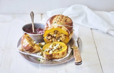 Een butternut-pompoen ligt op een schaal van inox. Hij is mooi opgevuld met een mengsel van krieltjes, preistukjes en blauweschimmelkaas. Wij combineren hem met veenbessencompote om een zoete smaak toe te voegen. 