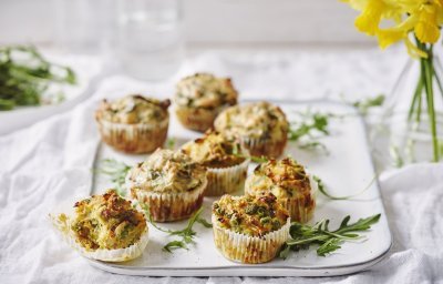 Hartige cupcakes op een dienplateau gepresenteerd. Achteraan staat een vaasje met Narcissen te schitteren.