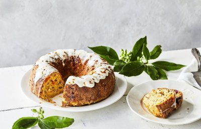 Een tulband cake met groenten als bijgerecht bij je middagmaal, dat is pas een feestmaaltijd! Wij maakten eentje met pompoen, rode biet, Belgische kaas en kastanjes. Hij staat op een witte houten tafel op een wit groot bord, de cake is afgewerkt met een garnering van zure room.