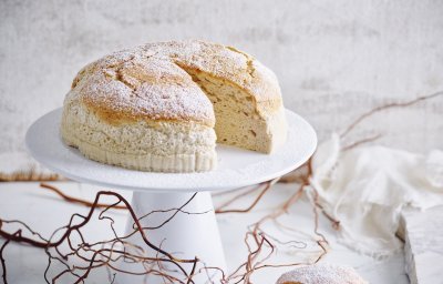 Een Japanse cheesecake, ook wel cheescakesoufflé genoemd, staat op een taartstandaard. Er is al 1 stukje aangesneden om meteen te smullen. 