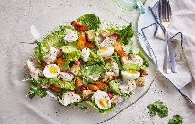 Een goed gevulde schaal met een groene salade, enkele oranje wortels en gekookte eitjes. Stukjes rode poon werden toegevoegd voor extra smaak, natuurlijk.