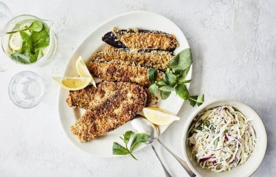 Vegetarische schnitzels gemaakt van aubergine. Ze liggen op een groot wit ovaal bord, waar je er eentje van kan afnemen. Wij serveren hem met een koolslaatje.