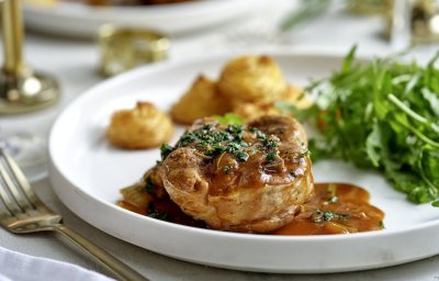 Het hoofdgerecht is geserveerd op een wit groot bord. Ieder krijgt een portie schenkel, pommes duchesse en frisse rucolasla. 