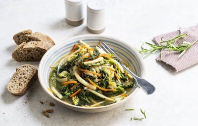 Op de tafel staat een portie uitgeschept van het vegetarische stoofpotje boordevol groenten. Denk maar aan witloof, savooikool, pastinaak en wortel. Wij serveren dit gerechtje met enkele sneetjes zuurdesembrood. 
