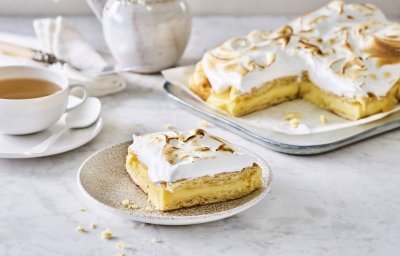 Croissanttaart staat aangesneden op tafel, thee is opgediend en bordjes staan klaar. De meringue is mooi gekleurd door de brulébrander. 