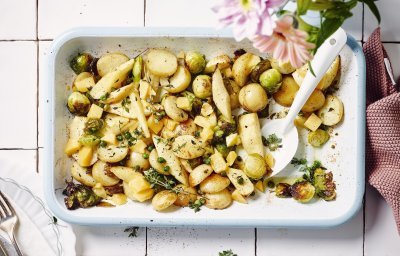 Een heerlijk geurende ovenschotel staat op het aanrecht. Het is een traybake van aardappelen met spruitjes, pastinaak en Beauvoordse brokkelkaas.