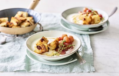 Een heerlijk én makkelijk ontbijtje staat klaar op tafel. De yoghurt is geserveerd in ontbijtkommetjes en afgewerkt met gegrilde druiven en krokante croutons van rozijnenbrood.