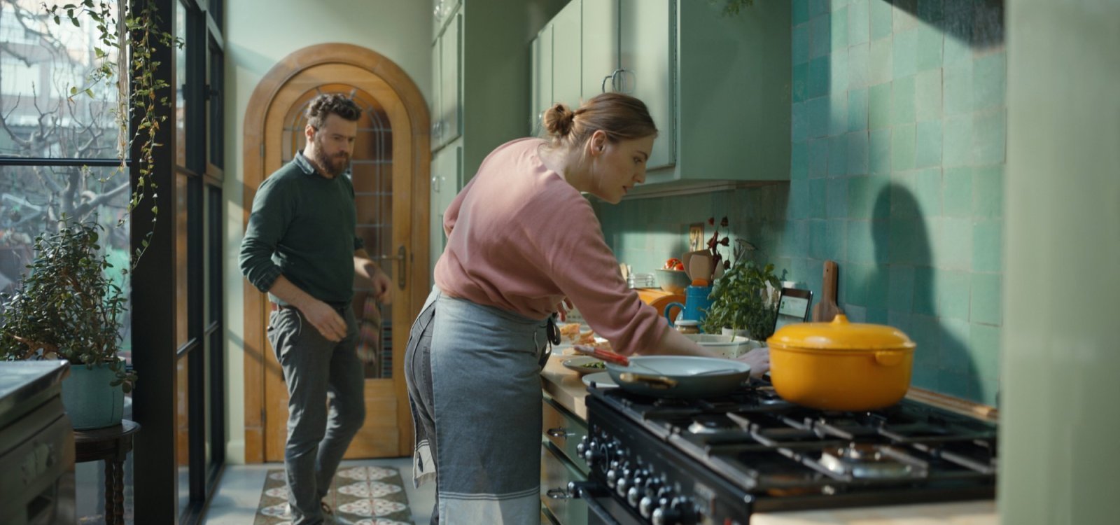 Vrouw kookt samen met haar man Vrouw staat te koken aan het fornuis terwijl haar man staat te wachten op instructies.
