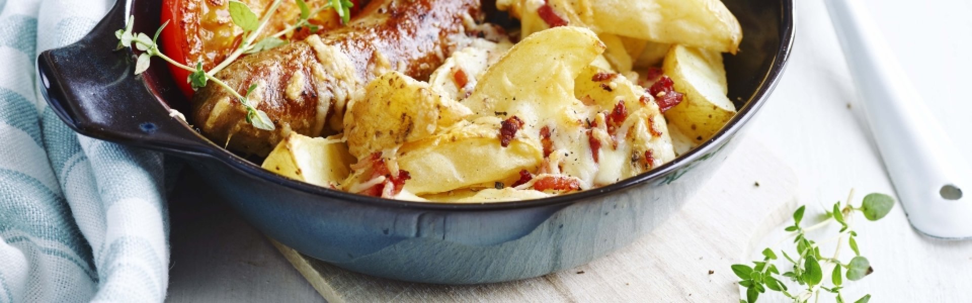 Quartiers de pommes de terre au fromage et crème épaisse, saucisse et tomates