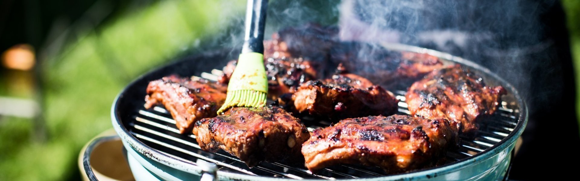 Ribbetjes op de bbq Ribbetjes op een barbecue in de tuin. De kok borstel nog wat marinade op het vlees.